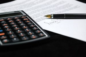 Calculator and pen resting on mortgage paperwork, symbolizing financial decisions faced by homeowners in Plano, Richardson, and Addison, Texas.